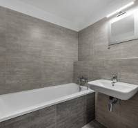 PREDAJ 2-IZBOVÉHO BYTU – NOVOSTAVBA JARABINKY, RUŽINOV - Kúpeľňa v 2-izbovom byte s vaňou, umývadlom a sivými obkladačkami.