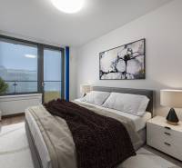 PREDAJ 2-IZBOVÉHO BYTU – NOVOSTAVBA JARABINKY, RUŽINOV - Spálňa v 2-izbovom byte s pohodlnou posteľou, obrazom a lampou na nočnom stolíku.