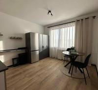 REZERVOVANÝ PREDAJ 1-izbový byt, Vlčince - okr. Žilina - Kuchyňa s podlahou s dreveným dekorom a stolom v 1-izbovom byte.