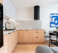 3i BYT V TOP LOKALITE – Trenčín, Sihoť - NA PRENÁJOM - Kuchyňa s podlahou s dreveným dekorom, drevenými skrinkami a jedálenským stolom v 3-izbovom byte.