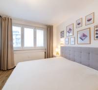 PREDAJ 2 izbový moderne zrekonštruovaný byt s klimatizáciou, CENTRUM - Svetlá spálňa s podlahou s dreveným dekorom, posteľou a nástennými obrazmi v 2-izbovom byte.