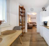 PREDAJ 2 izbový moderne zrekonštruovaný byt s klimatizáciou, CENTRUM - Kuchyňa v 2-izbovom byte s jedálenským stolom, policou a podlahou s dreveným dekorom.