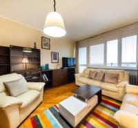 NA PREDAJ 3-izbový byt v centre, jedinečný výhľad na mesto, Nitra - Obývačka v 3-izbovom byte s pohovkami, farebným kobercom a podlahou s dreveným dekorom.