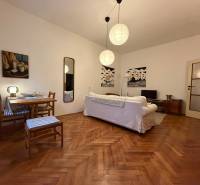 – PRENAJOM – 2 IZBOVÝ BYT – PANENSKÁ – STARE MESTO - Obývacia izba v 2-izbovom byte s podlahou s dreveným dekorom, bielou sedačkou a stolom.