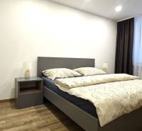 Prenájom komfortný, zariadený 3 izbový byt po úplnej rekonštrukcii - Spálňa s posteľou, nočným stolíkom a podlahou s dreveným dekorom v 3-izbovom byte.