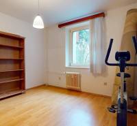 Veľkometrážny 3i byt s výťahom a pivnicou | Ružinov | 82m2 - Izba v 3-izbovom byte so skriňou, kobercami a stacionárnym bicyklom, podlaha s dreveným dekorom.