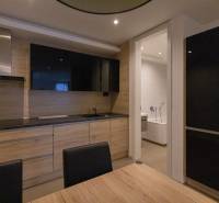 Exkluzívny 2i byt s terasou a parkovaním, Kramáre - Kuchyňa v 2-izbovom byte s podlahou s dreveným dekorom a inštalovanou televíziou.