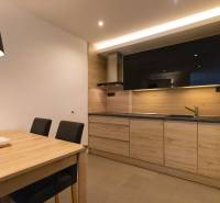 Exkluzívny 2i byt s terasou a parkovaním, Kramáre - Kuchyňa 2-izbového bytu s minimalistickým dizajnom, dreveným dekorom a jedálenským stolom.