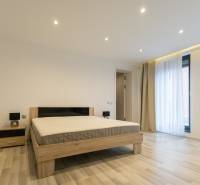 Exkluzívny 2i byt s terasou a parkovaním, Kramáre - Spálňa v 2-izbovom byte s posteľou, nočným stolíkom a podlahou s dreveným dekorom.