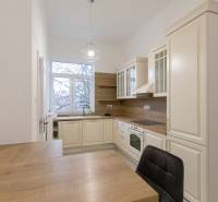 Priestranný 3i byt s vysokými stropmi, Dunajská - Kuchyňa v 3-izbovom byte s podlahou s dreveným dekorom a klasickými kuchynskými skrinkami.