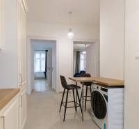 Priestranný 3i byt s vysokými stropmi, Dunajská - Chodba v 3-izbovom byte s práčkou, stoličkami a kuchynskou linkou.