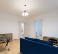 Priestranný 3i byt s vysokými stropmi, Dunajská - Obývacia izba v 3-izbovom byte s podlahou s dreveným dekorom a modrou pohovkou.