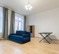 Priestranný 3i byt s vysokými stropmi, Dunajská - Obývacia izba s modrou sedačkou a podlahou s dreveným dekorom v 3-izbovom byte.