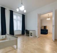 Priestranný 3i byt s vysokými stropmi, Dunajská - Interiér 3-izbového bytu s podlahou s dreveným dekorom, nábytkom a lustrom.