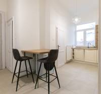 Priestranný 3i byt s vysokými stropmi, Dunajská - Kuchyňa v 3-izbovom byte s barovým pultom, dvoma stoličkami a veľkým oknom.