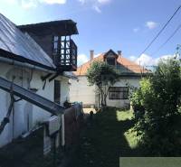 Rodinný dom v srdci Štiavnických vrchov, Štiavnické Bane. - Záhrada rodinného domu v Štiavnických Baniach s drevenou verandou a kvitnúcimi stromami.