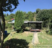 Rodinný dom v srdci Štiavnických vrchov, Štiavnické Bane. - Záhrada rodinného domu v Štiavnických Baniach s altánkom, stromami a pňom.