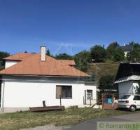 Rodinný dom v srdci Štiavnických vrchov, Štiavnické Bane. - Rodinný dom v Štiavnických Baniach s plechovou strechou, autom a stromami v pozadí.