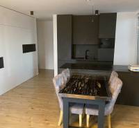 3-izb. byt, Zuzany Chalupovej, Petržalkou s veľkou terasou a saunou - Jedálenský kút s mramorovým stolom a kuchynskou linkou v 3-izbovom byte s podlahou s dreveným dekorom.