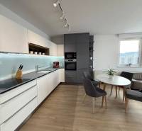 3-izb. byt, Martina Granca, Dúbravka, novostavba Pekná výhliadka - Kuchyňa v 3-izbovom byte s podlahou s dreveným dekorom a jedálenským stolom.