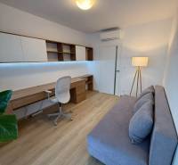 3-izb. byt, Martina Granca, Dúbravka, novostavba Pekná výhliadka - Pracovňa v 3-izbovom byte s podlahou s dreveným dekorom, sivou pohovkou a písacím stolom.