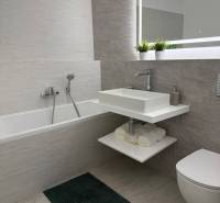 3-izb. byt, Martina Granca, Dúbravka, novostavba Pekná výhliadka - Kúpeľňa s vaňou, zrkadlom a umývadlom v 3-izbovom byte; tmavý koberec, svetlé obklady.