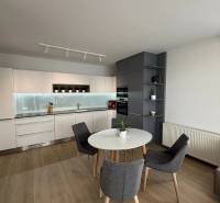3-izb. byt, Martina Granca, Dúbravka, novostavba Pekná výhliadka - Kuchyňa v 3-izbovom byte s bielymi skrinkami, okrúhlym stolom a podlahou s dreveným dekorom.