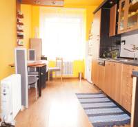 Veľký 1-izb. byt v tehlovom dome, Miletičova ul., Ružinov  - Kuchyňa v 1-izbovom byte s dreveným dekorom, jedálenským stolom a žltou stenou.