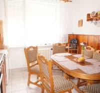 Rodinný dom v obci Čilížska Radváň s veľkým pozemkom - Kuchyňa rodinného domu s dreveným obložením, jedálenským stolom a nástennými dekoráciami.