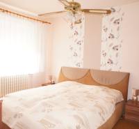 Rodinný dom v obci Čilížska Radváň s veľkým pozemkom - Spálňu v rodinnom dome zdobí posteľ, nočné stolíky a záclony na okne.