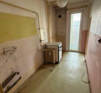 4-izb. byt, Martinčekova ul., Ružinov, 2.p./10, 2 x lodžia - Stará kuchyňa v 4-izbovom byte s opotrebovanými stenami a sporákom pri okne.