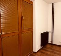 Garzónka M. Schneidra Trnavského, Dúbravka, veľká lodžia - Garsónka s hnedými žalúziami, dverami a podlahou s dreveným dekorom, radiátor v rohu.