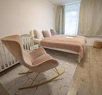 2,5 izb. byt, ul. Jelenia, Staré Mesto,tehlový dom, po rekonštrukcii - Spálňa s posteľou, drevenou podlahou, detskou postieľkou a hojdacím kreslom, na ulici Jelenia.