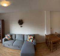 3-izb. byt, Palkovičova ul., Ružinov, lodžia, 4.p./12 - Priestranný obývací priestor s kuchyňou, jedálenským stolom a podlahou s dreveným dekorom.