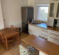 3-izb. byt, Palkovičova ul., Ružinov, lodžia, 4.p./12 - Kuchyňa v 3-izbovom byte s barovým pultom, jedálenským stolom a podlahou s dreveným dekorom.