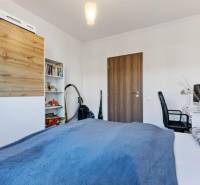 Novostavba 3-izb. bytu s parkovacím státím, ul.Hany Ponickej, Lamač - Spálňa v 3-izbovom byte s pracovným stolom, posteľou a skriňou s dreveným dekorom.