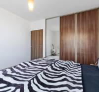 Novostavba 3-izb. bytu s parkovacím státím, ul.Hany Ponickej, Lamač - Spálňa s posteľou a veľkou skriňou v 3-izbovom byte, vešiak s ozdobnými vankúšmi.