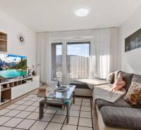 Novostavba 3-izb. bytu s parkovacím státím, ul.Hany Ponickej, Lamač - Obývačka v 3-izbovom byte s pohodlným sedením a stolíkom, podlaha s dreveným dekorom.