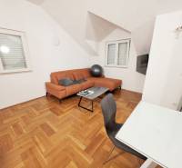 Chorvátsko, Makarska - zariadený apartmán s výhľadom na more - Rekreačný apartmán s oranžovou sedačkou a podlahou s dreveným dekorom.