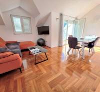 Chorvátsko, Makarska - zariadený apartmán s výhľadom na more - Rekreačný apartmán s oranžovou pohovkou, jedálenským stolom a podlahou s dreveným dekorom.