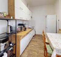 Priestranný 3 izbový byt s dvomi balkónmi, BA III. Kramáre, Stromová - Kuchyňa v 3-izbovom byte s podlahou s dreveným dekorom, jedálenským stolom a bielymi skrinkami.