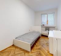 Priestranný 3 izbový byt s dvomi balkónmi, BA III. Kramáre, Stromová - Jednoduchá izba s posteľou, stolom a podlahou s dreveným dekorom v 3-izbovom byte.