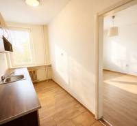 NA PREDAJ 1-IZB. BYT (28m2), BRATISLAVSKÁ UL., HOLÍČ - Kuchyňa v 1-izbovom byte s podlahou s dreveným dekorom a svetlom z okna.