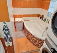 Predaj 2i byt v meste Kremnica, 64m2 - Kúpeľňa s vaňou a práčkou v 2-izbovom byte s oranžovými obkladačkami.