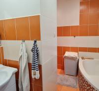 Predaj 2i byt v meste Kremnica, 64m2 - Kúpeľňa v 2-izbovom byte s oranžovo-bielymi obkladačkami a rohovou vaňou.