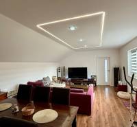 Rodinný dom v Bratislave – Podunajské Biskupice - Obývacia izba v rodinnom dome s pohodlným nábytkom a podlahou s dreveným dekorom.