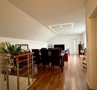 Rodinný dom v Bratislave – Podunajské Biskupice - Obývacia izba s podlahou s dreveným dekorom a jedálenským stolom v rodinnom dome.