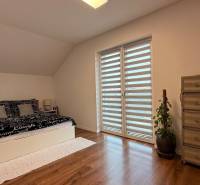 Rodinný dom v Bratislave – Podunajské Biskupice - Spálňa v rodinnom dome s posteľou, komodou a podlahou s dreveným dekorom.