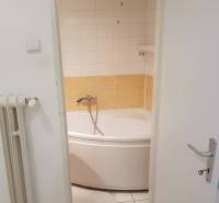 PREDAJ 2 IZBOVÝ BYT HANDLOVÁ  - Kúpeľňa s rohovou vaňou v 2-izbovom byte, vidieť radiátor a dvere.