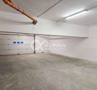 EXKLUZÍVNE 2i apartmán s terasou, garážovým státím, Veľká Lomnica - Priestranná uzavretá garáž v podzemí s bielymi stenami a kovovými garážovými dverami.